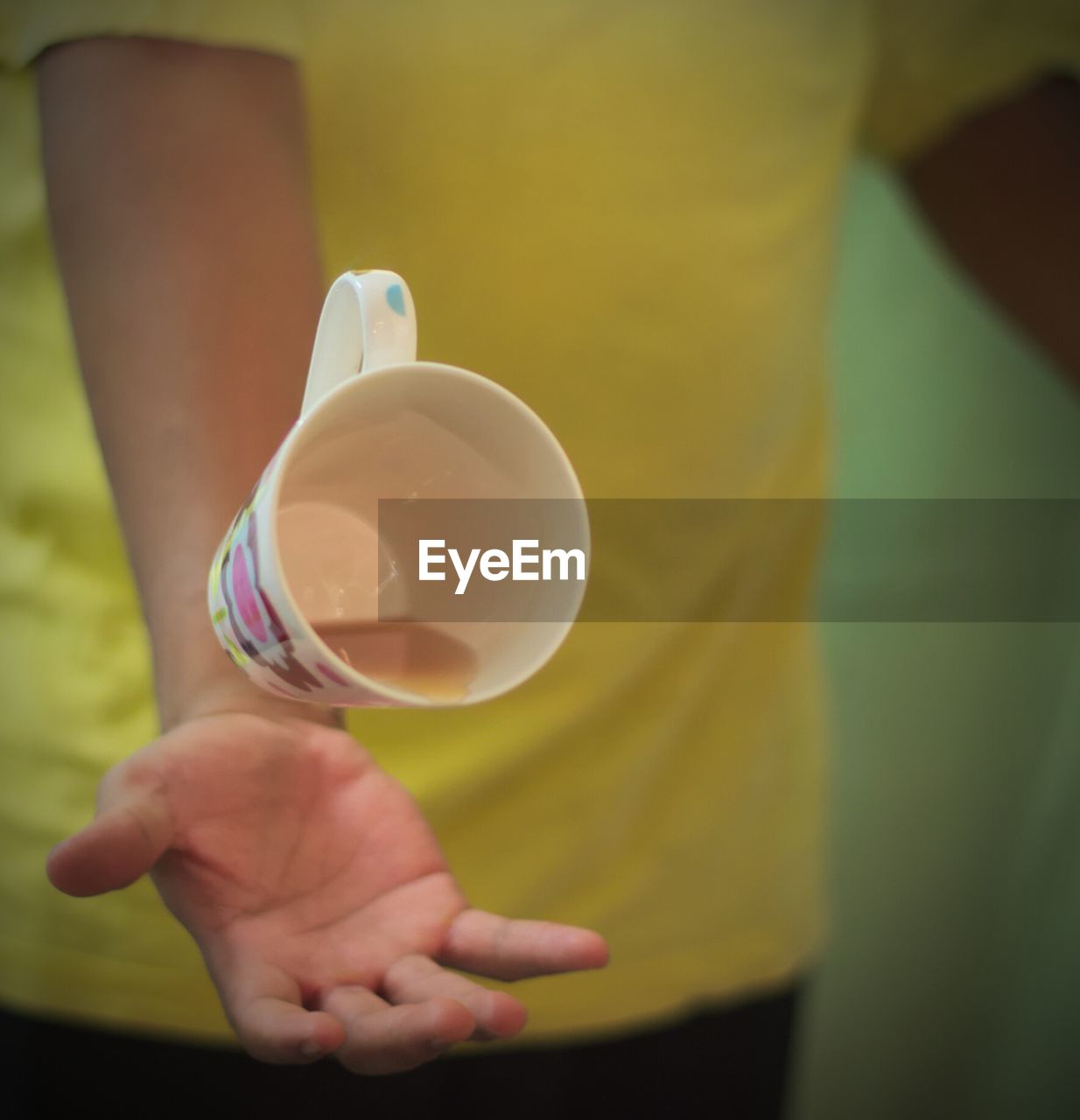 CLOSE-UP OF HAND HOLDING CUP OF CAKE