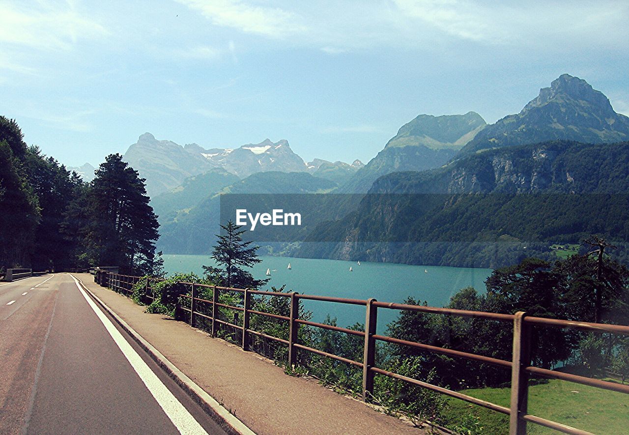 Empty road by lake against sky