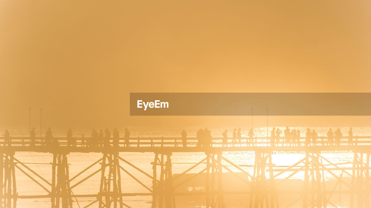 Silhouette people walking on mon bridge at sangkhla buri district against sky