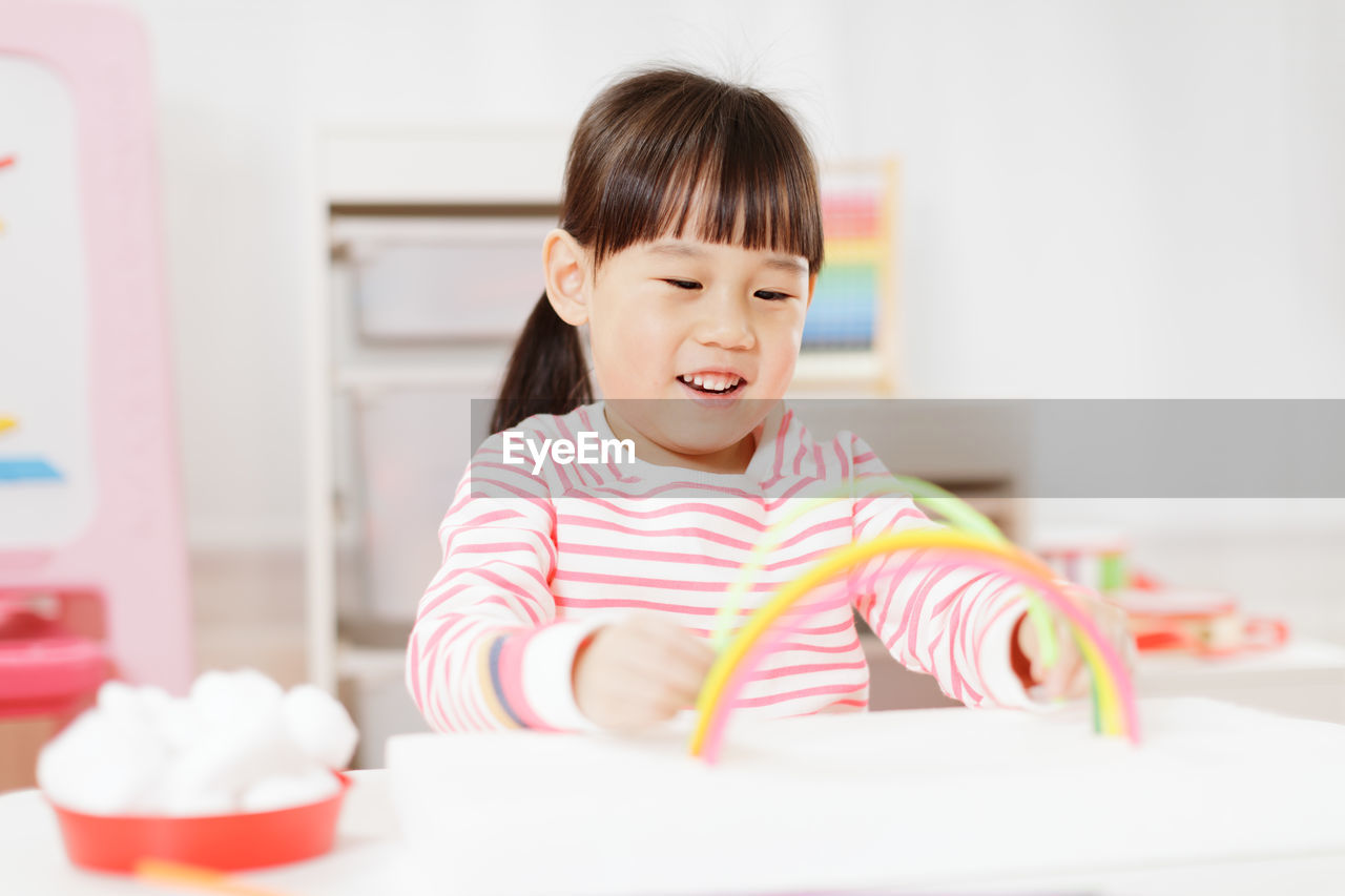 Young girl making rainbow craft using pipe cleaner at home