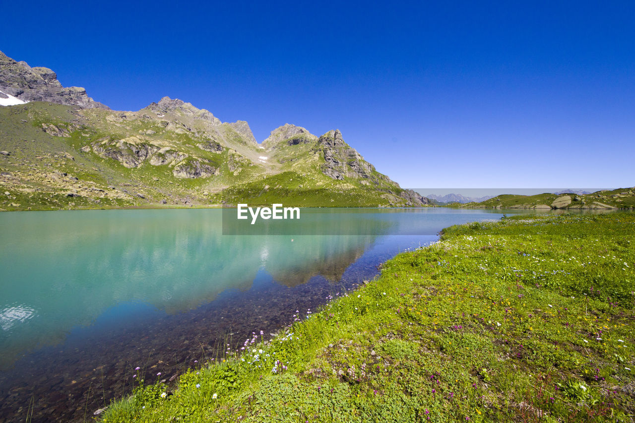 Scenic view of lake against clear blue sky