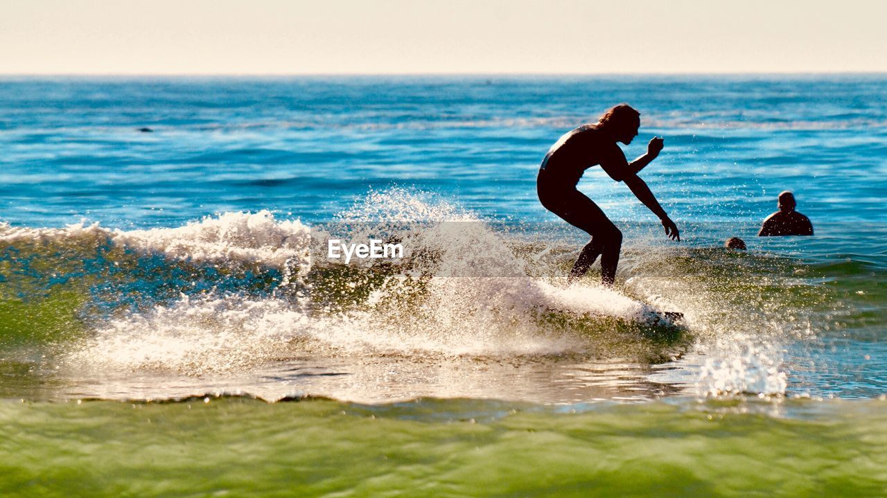 MEN PLAYING ON BEACH AGAINST SKY