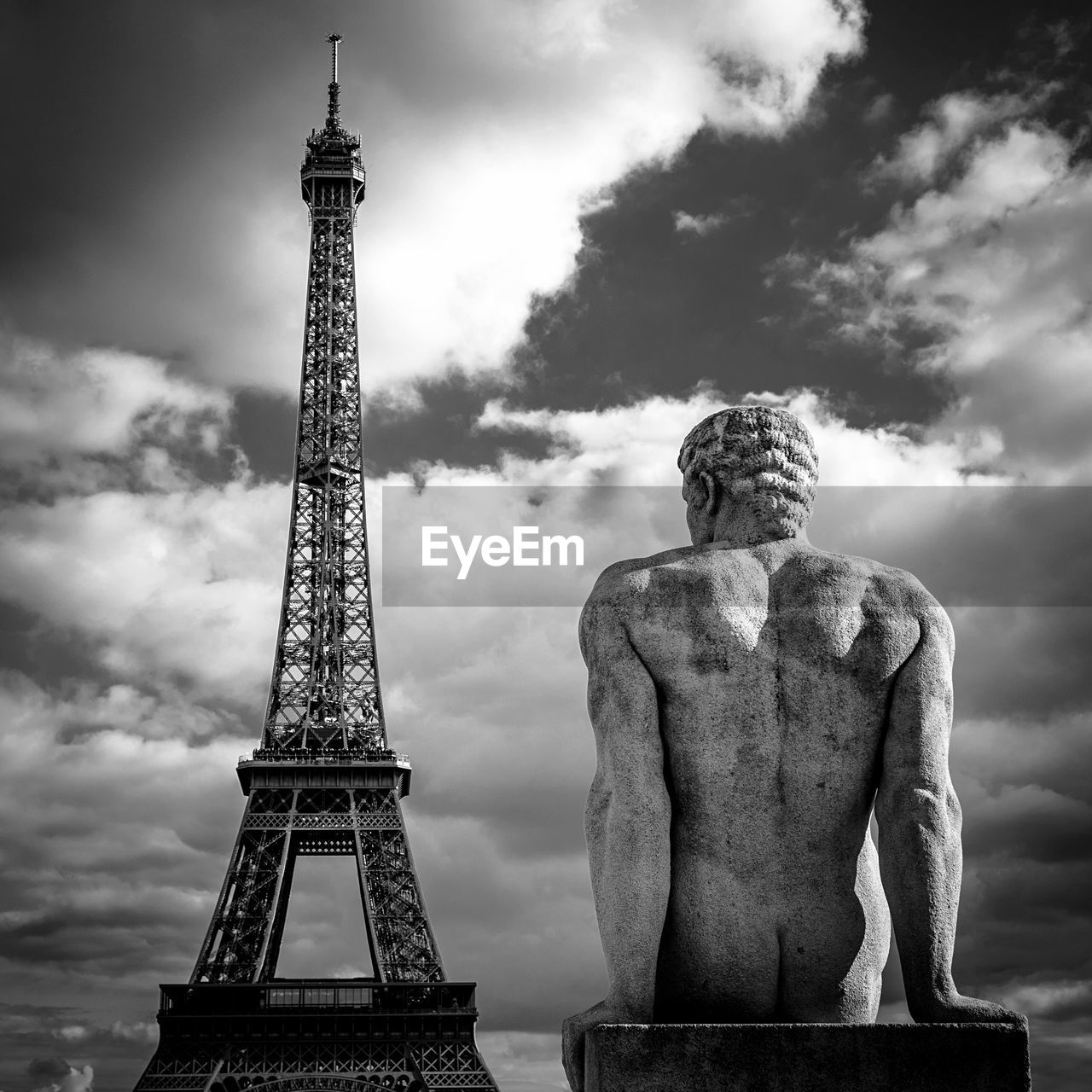 Low angle view of male sculpture in front of eiffel tower against sky