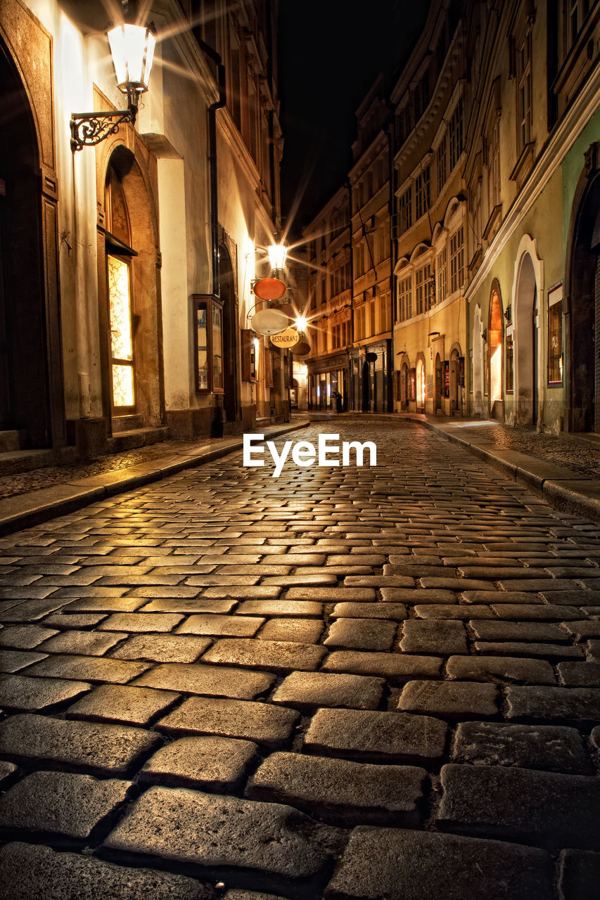 VIEW OF STREET AMIDST BUILDINGS AT NIGHT