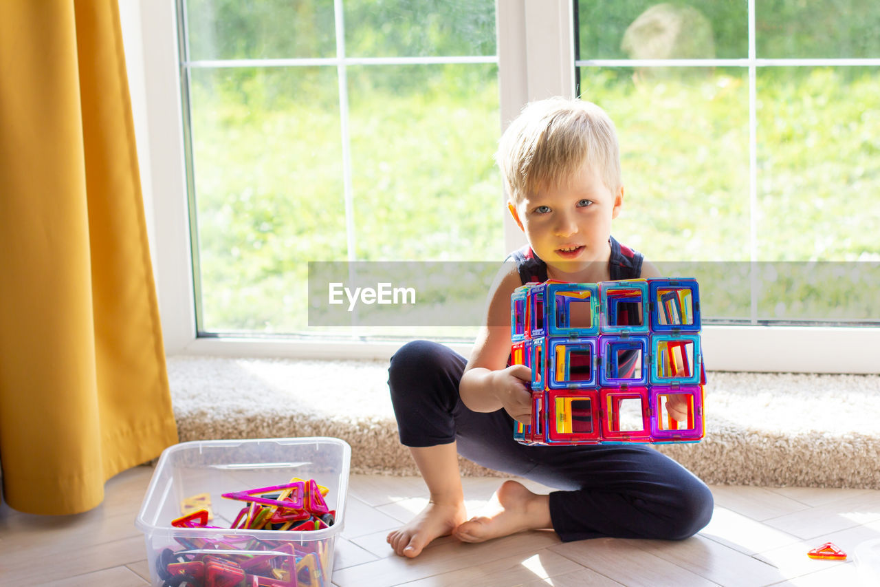 The child is playing with a multi-colored magnetic constructor, building a tower. educational toys 