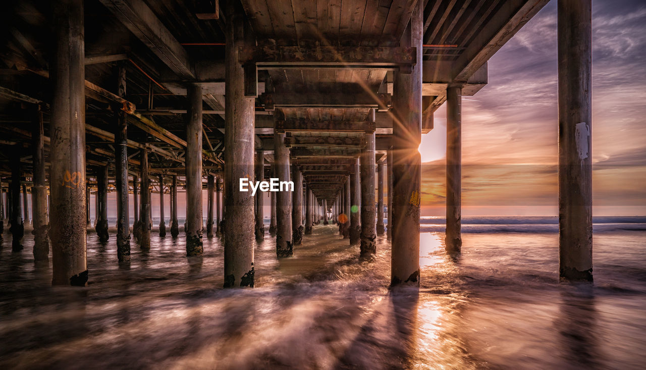 Pier at beach during sunset