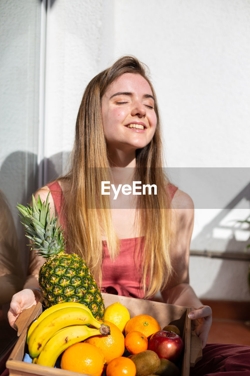 Woman carrying fruits in crate at home