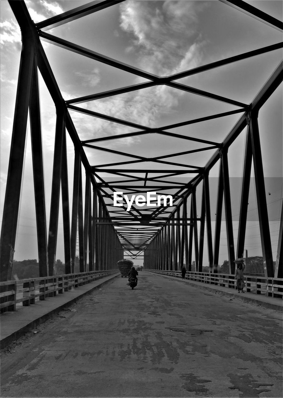 FULL LENGTH REAR VIEW OF MAN WALKING ON FOOTBRIDGE