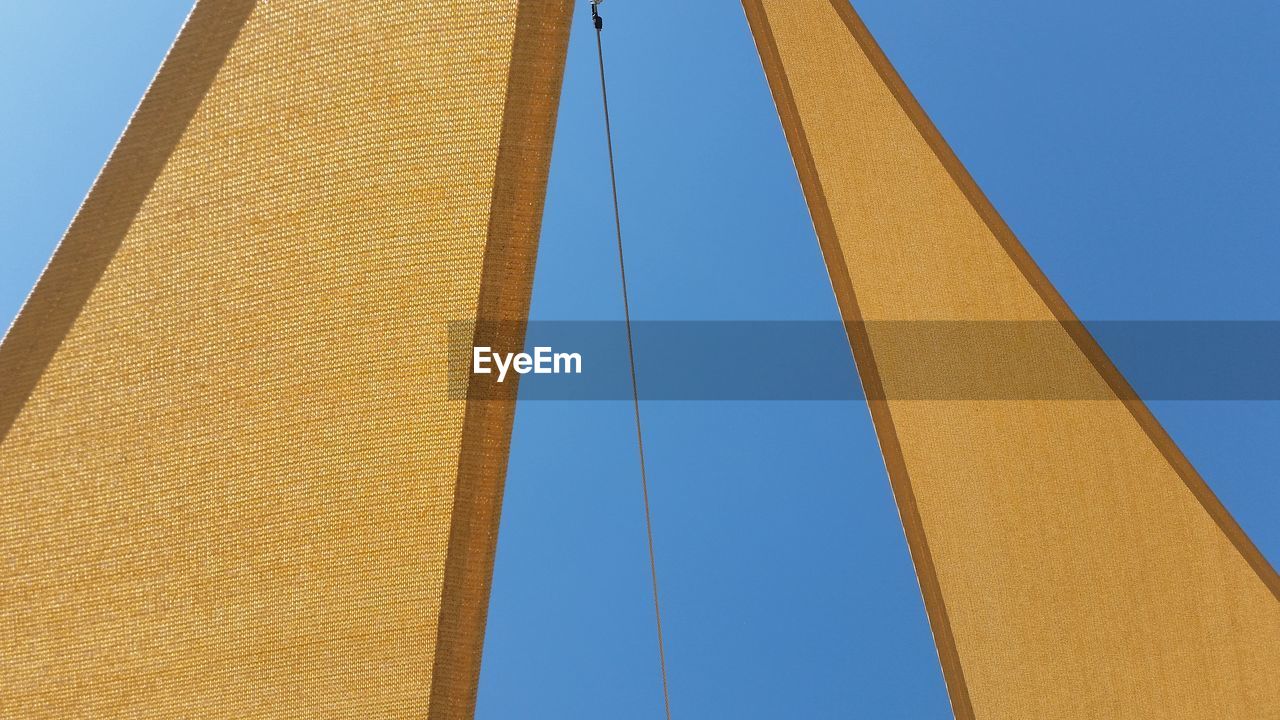 Low angle view of sailboat canvas against clear blue sky on sunny day