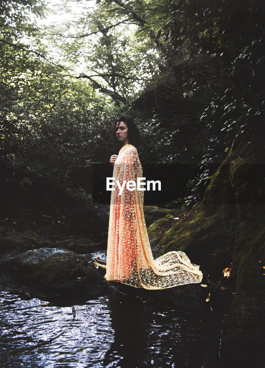 Portrait of woman standing on rock in forest