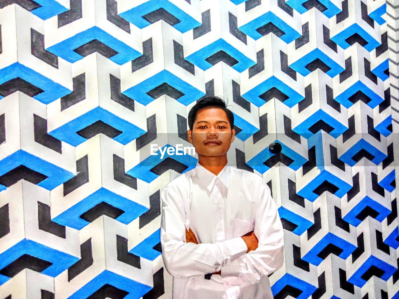 Portrait of smiling young man standing against wall