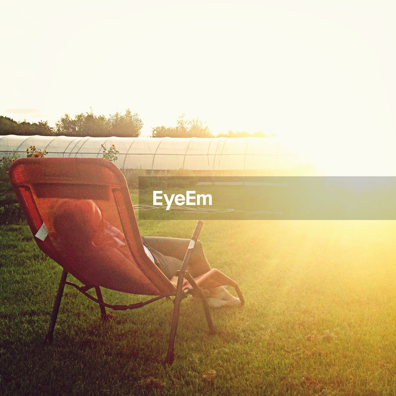 Woman sleeping on lounge chair in back yard with bright sunlight