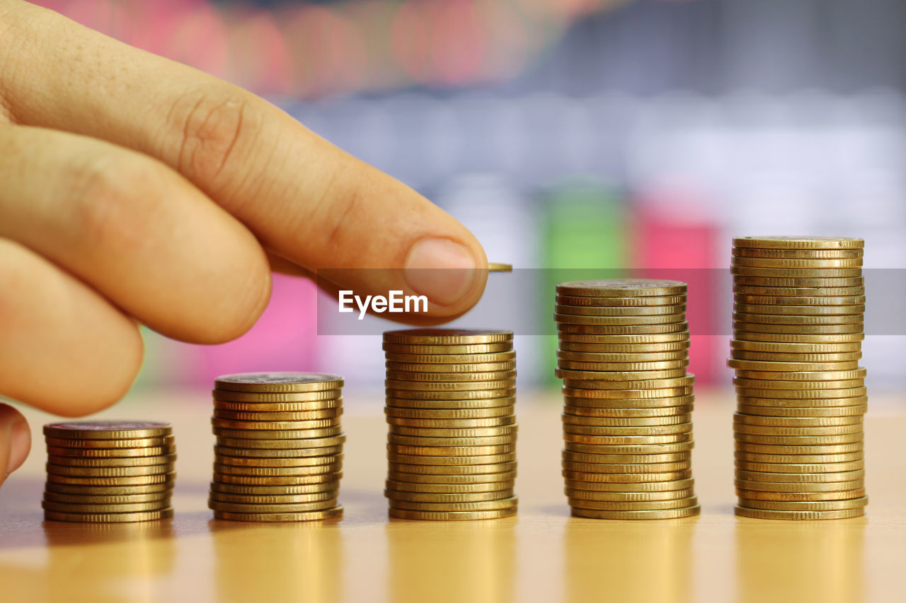 Close-up of hand stacking golden coins on table