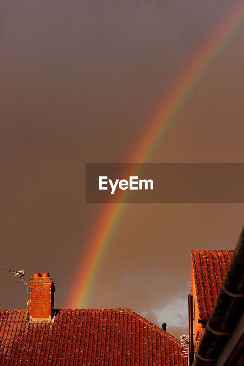 Houses against rainbow in sky at dusk