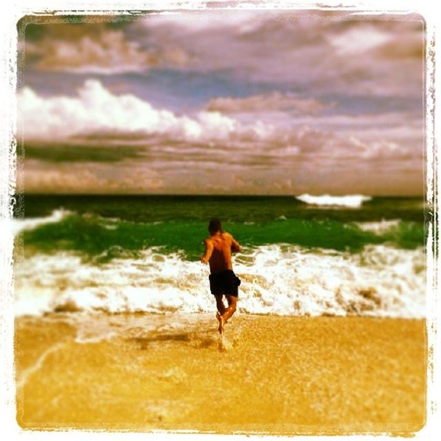 REAR VIEW OF MAN STANDING ON SEA