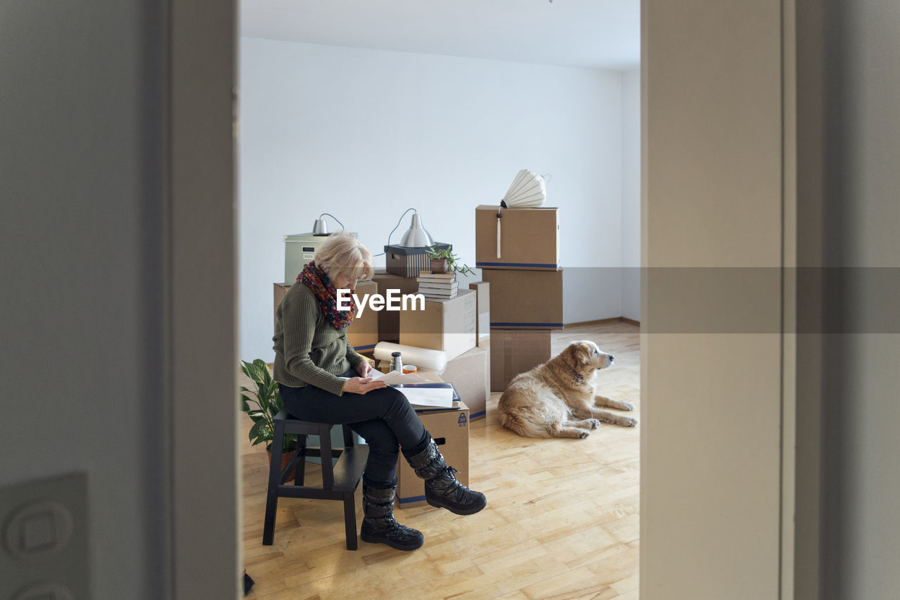 Senior woman looking at papers surrounded by cardboard boxes in an empty room