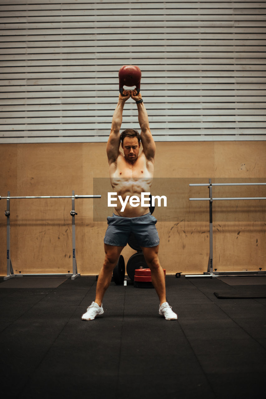 Shirtless man exercising in gym