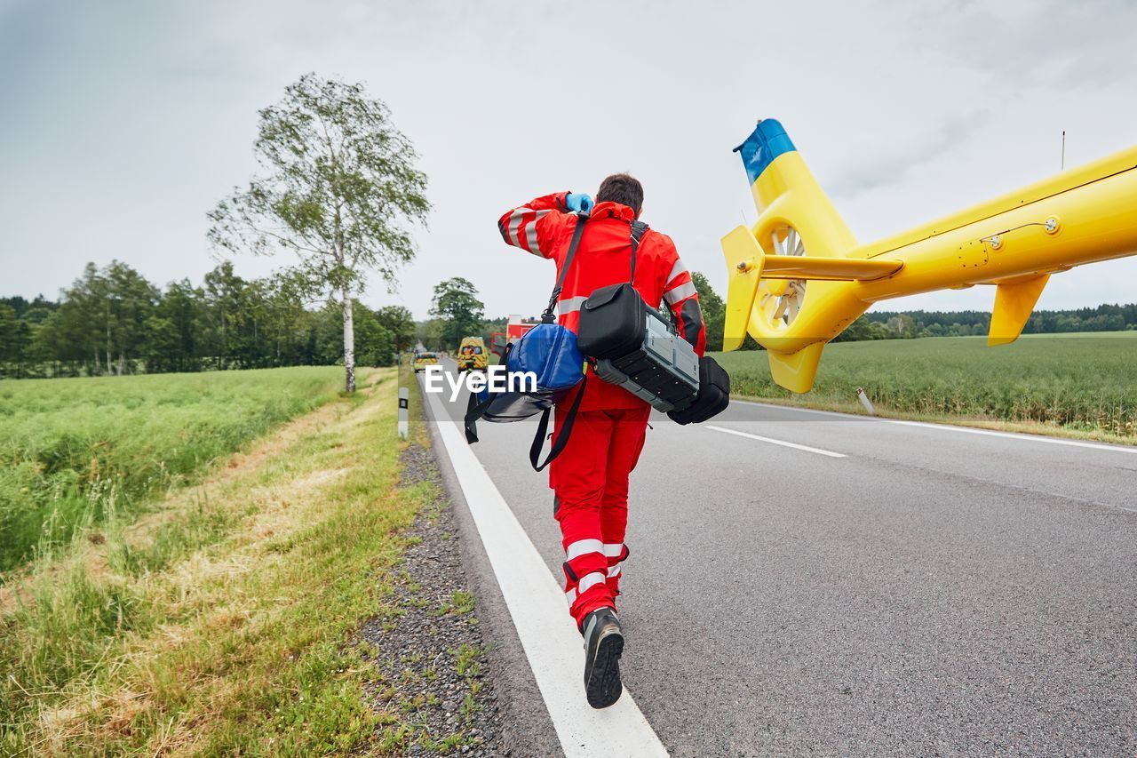 Man with bags walking on road against sky