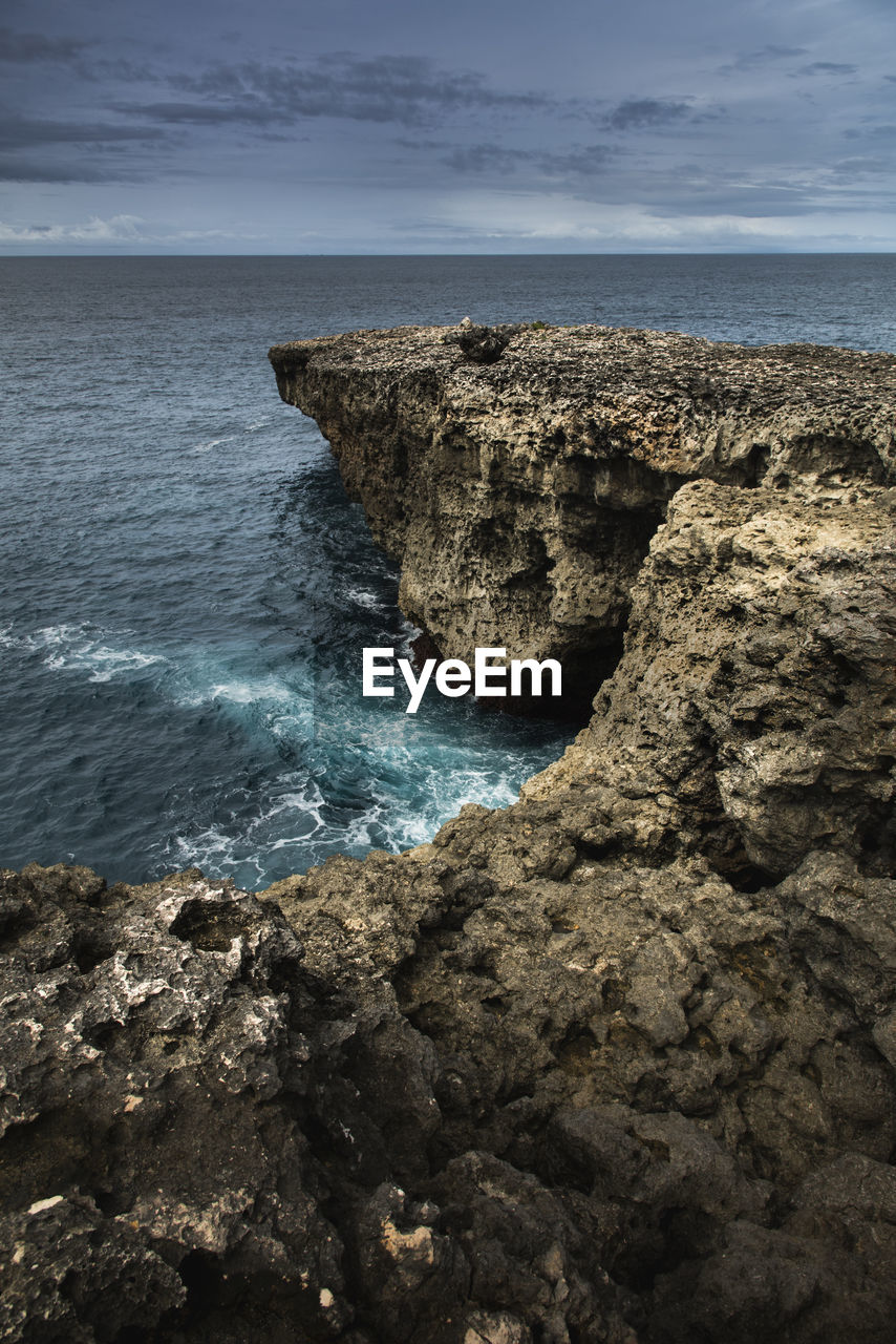 Rock formation on sea shore against sky