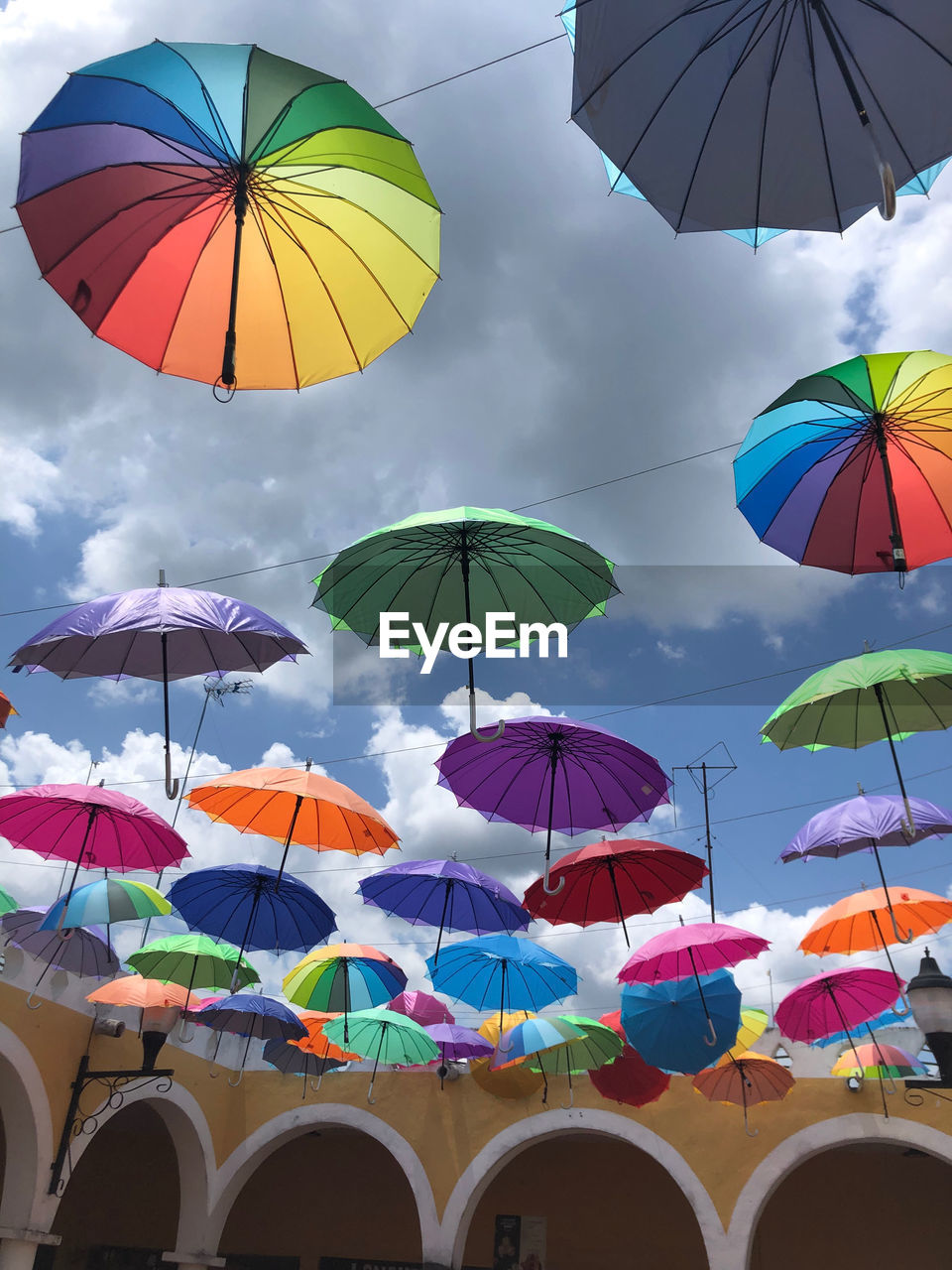 umbrella, protection, security, fashion accessory, parasol, multi colored, rain, sky, cloud, nature, wet, sunshade, low angle view, architecture, in a row, large group of objects, day, outdoors, shade, beach umbrella, no people, water, variation