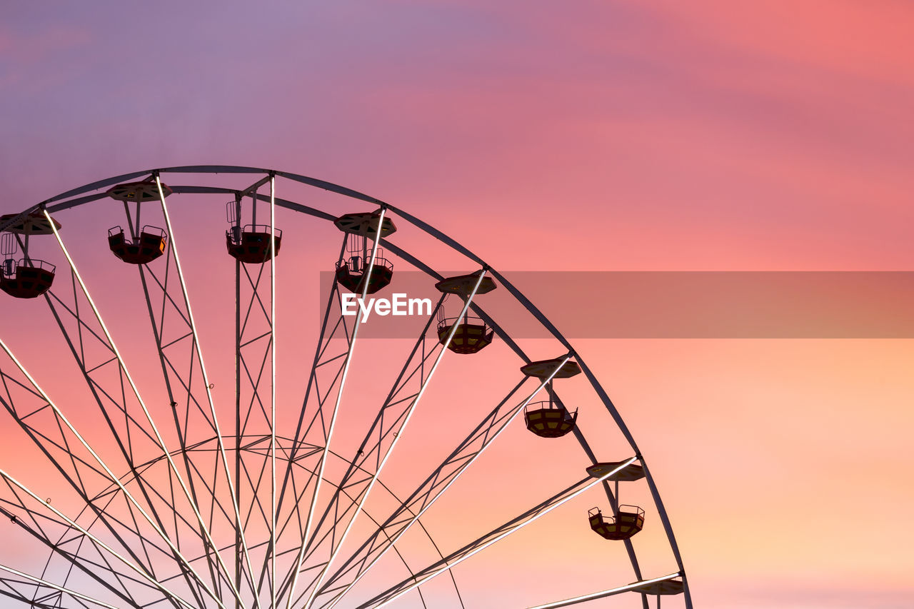 Low angle view of ferris wheel against sky at sunset