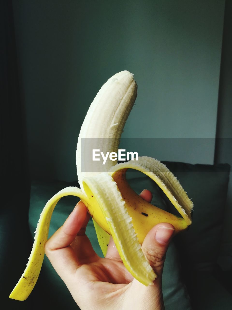 CLOSE-UP OF HAND HOLDING YELLOW FRUIT IN CONTAINER