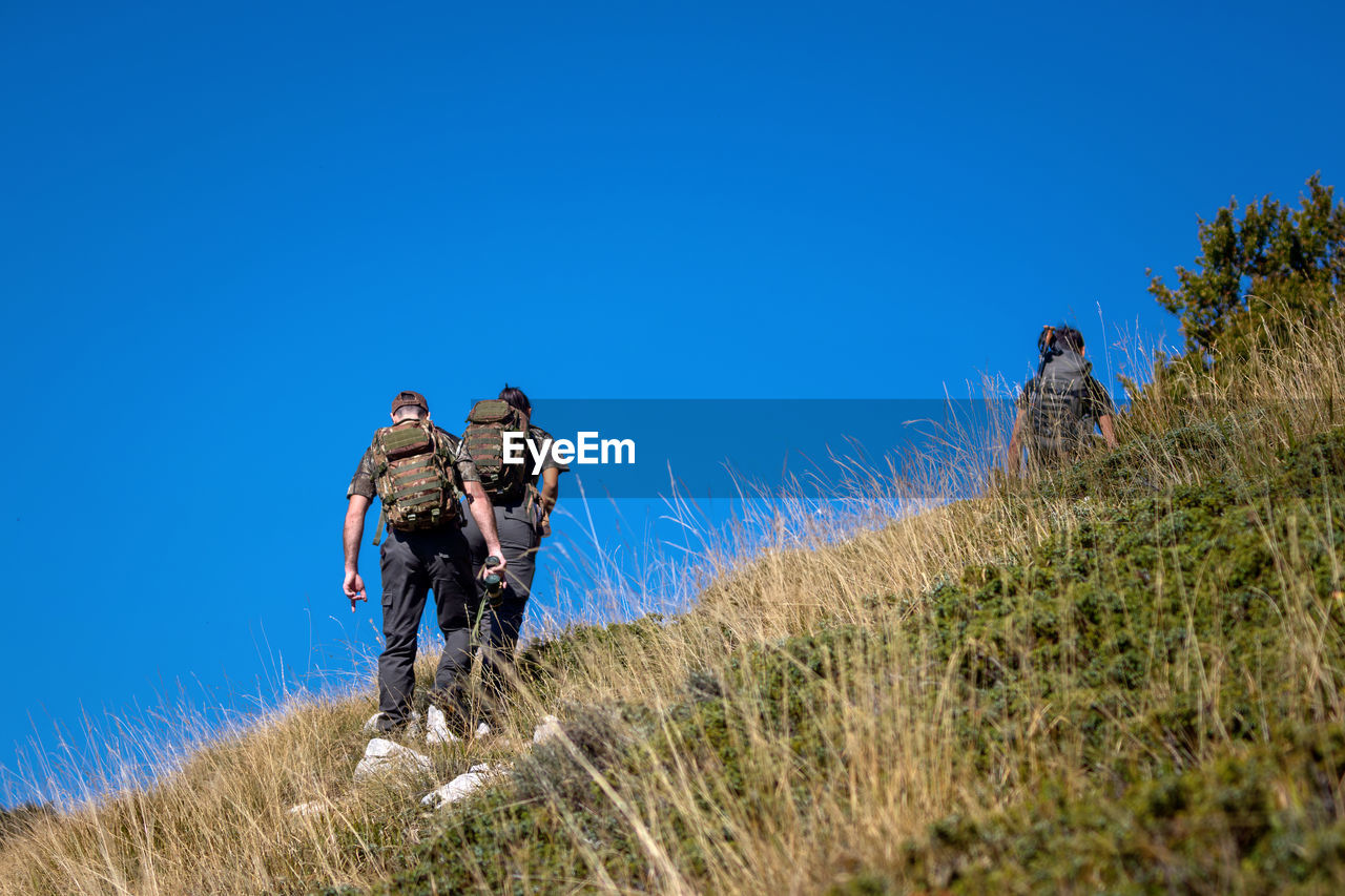 Hikers with backpacks on their shoulders walk up the mountain. blue sky in the background.