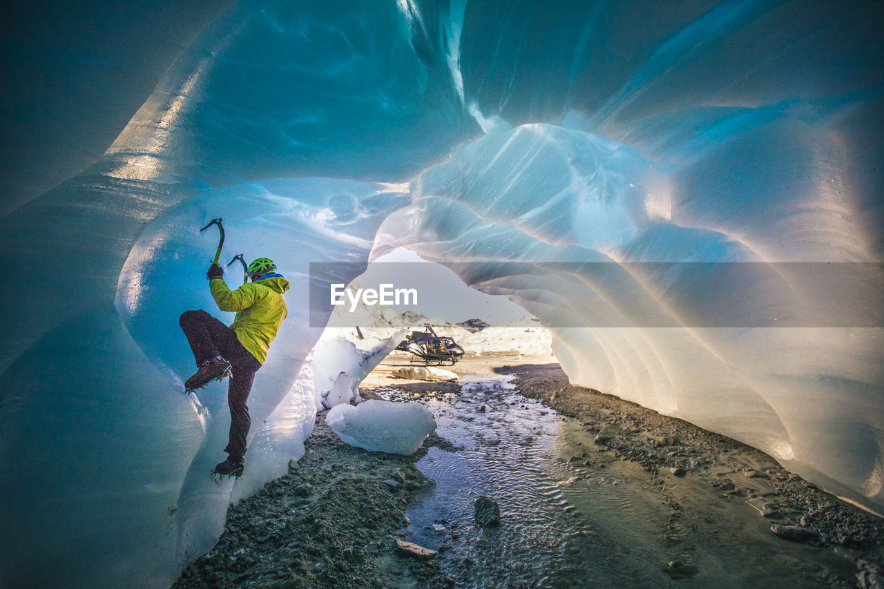 Man ice climbing in cave during luxury adventure tour.