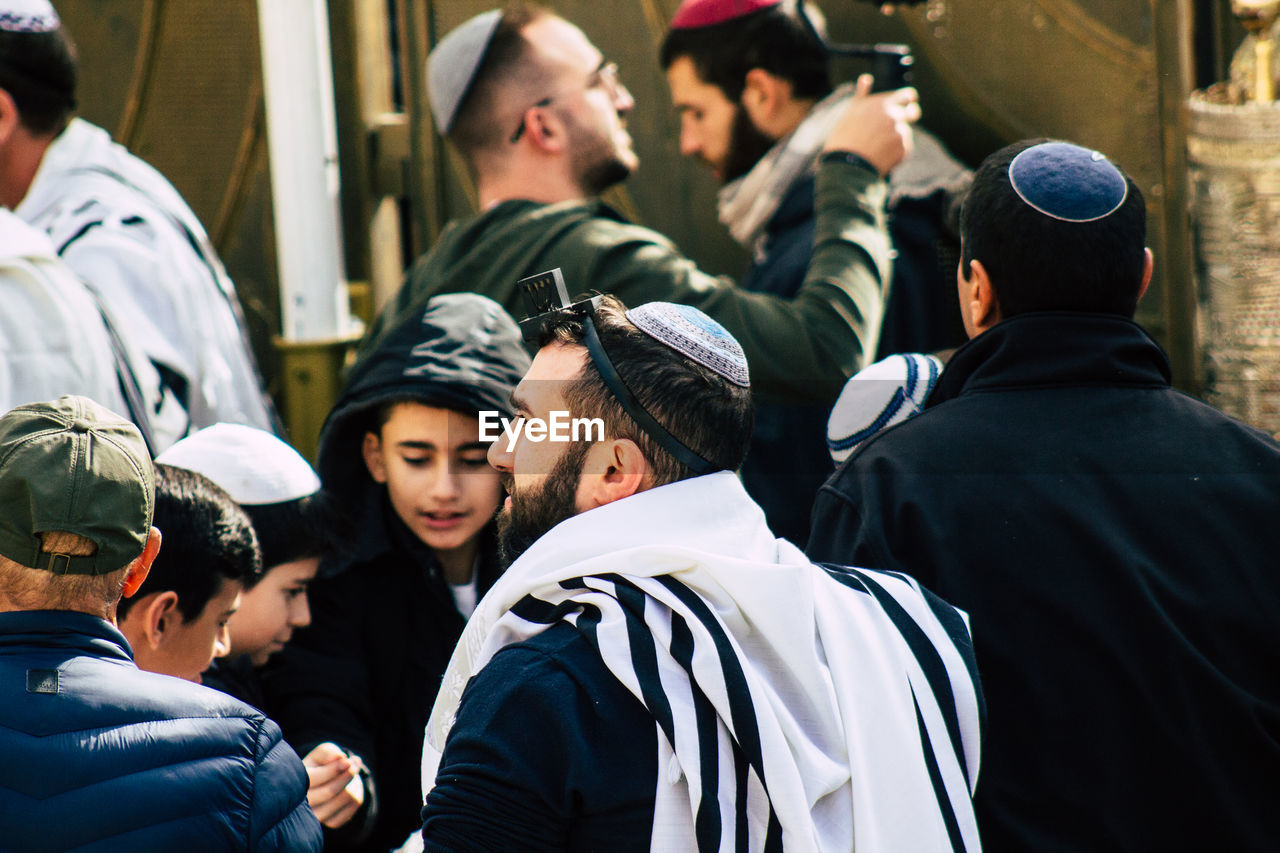 REAR VIEW OF PEOPLE STANDING IN FRONT OF A CITY