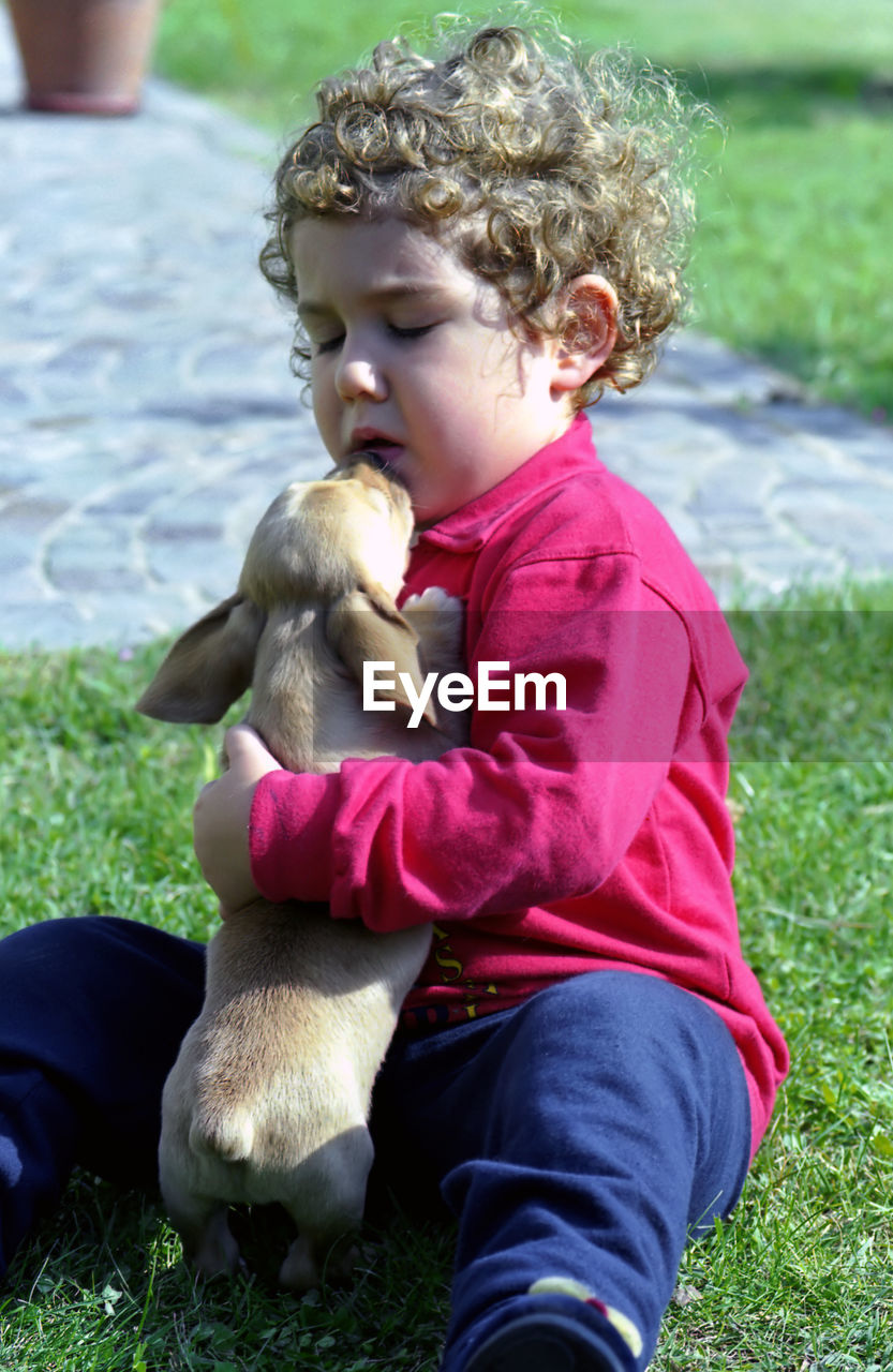 Cute boy sitting with dog on grass outdoors