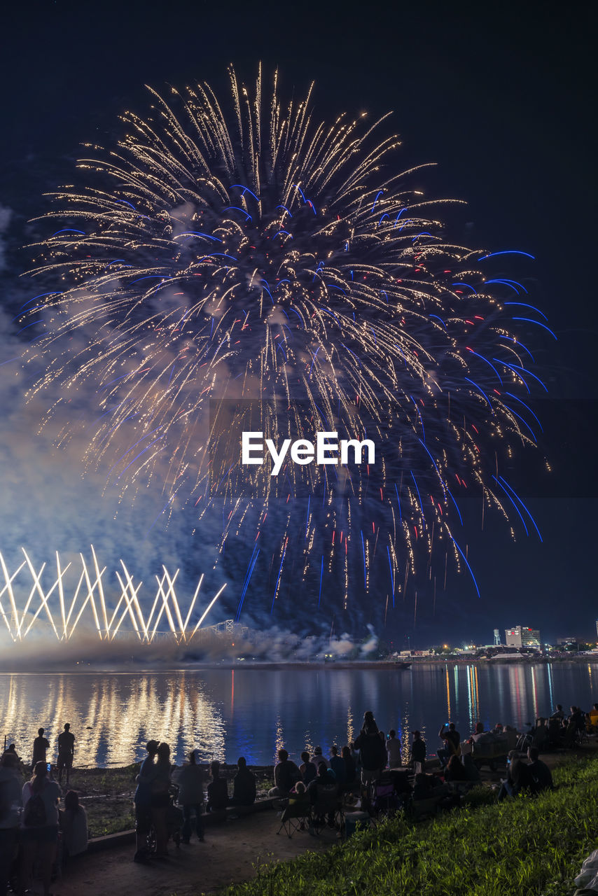 Crowd watching firework display at night