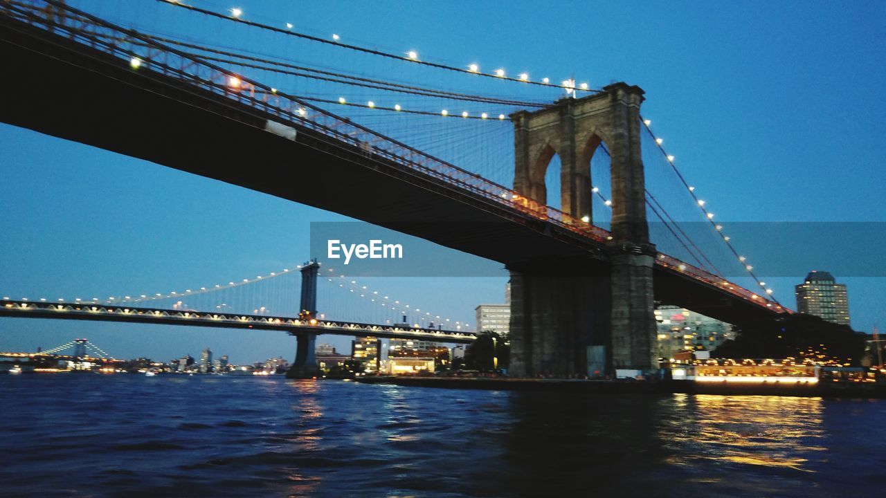 LOW ANGLE VIEW OF SUSPENSION BRIDGE OVER RIVER