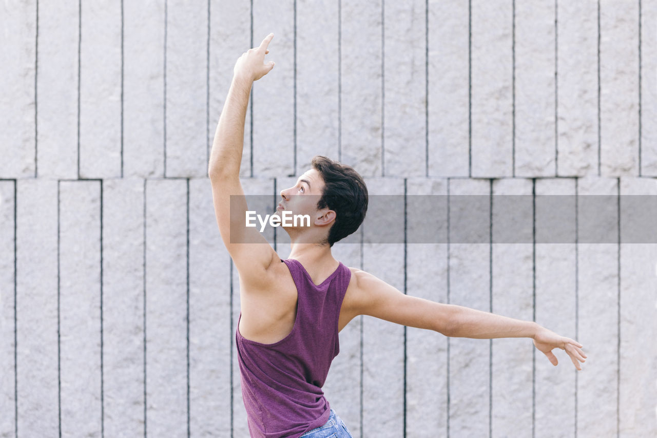 Rear view of young man dancing against wall