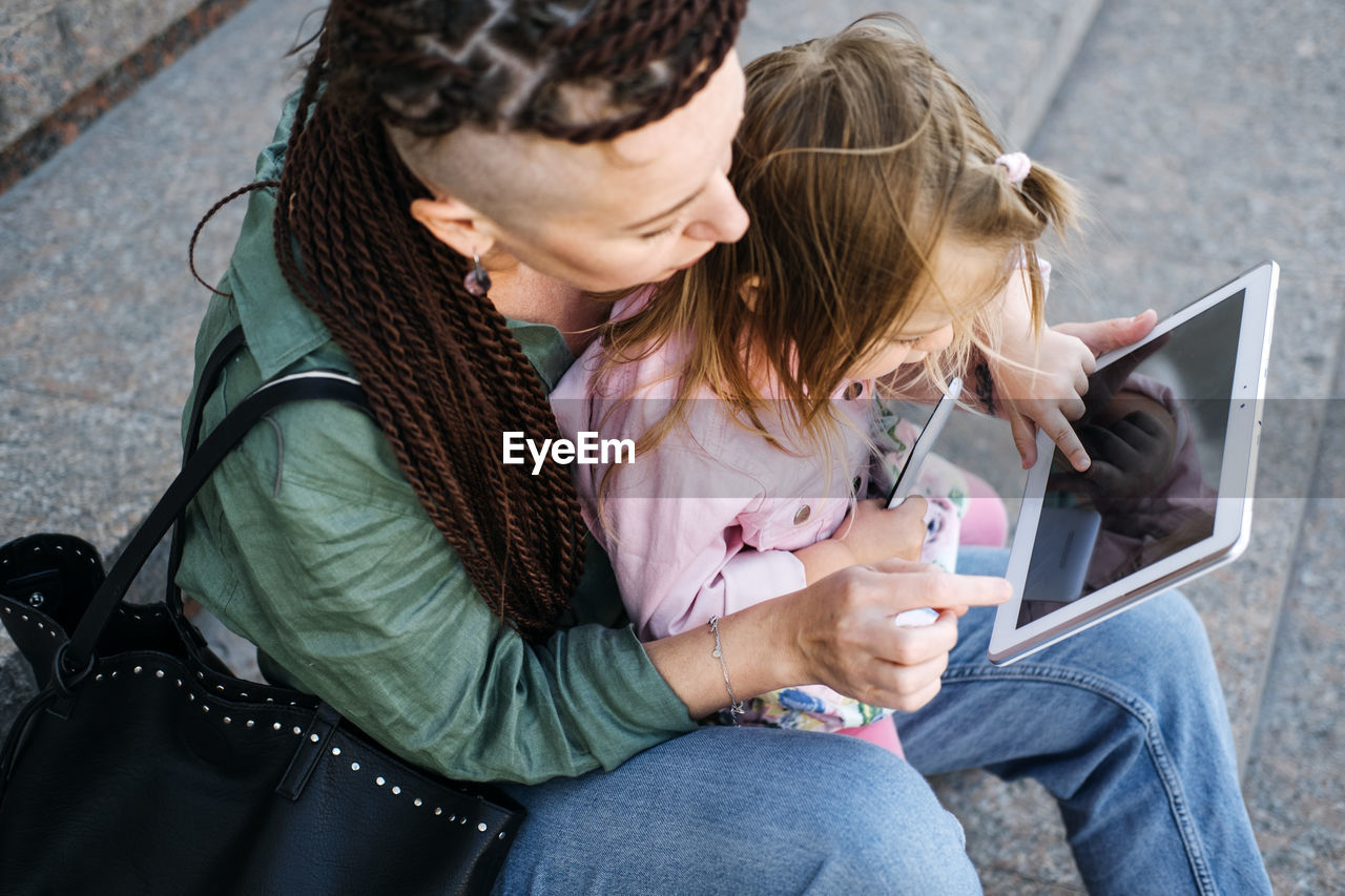 Freelance parents. busy working mom with baby toddler daughter on hands walk and looking on tablet