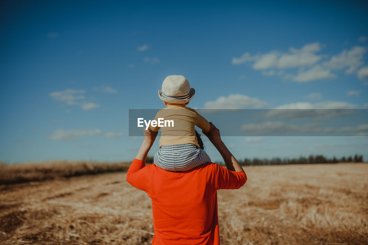 REAR VIEW OF MAN STANDING ON LAND