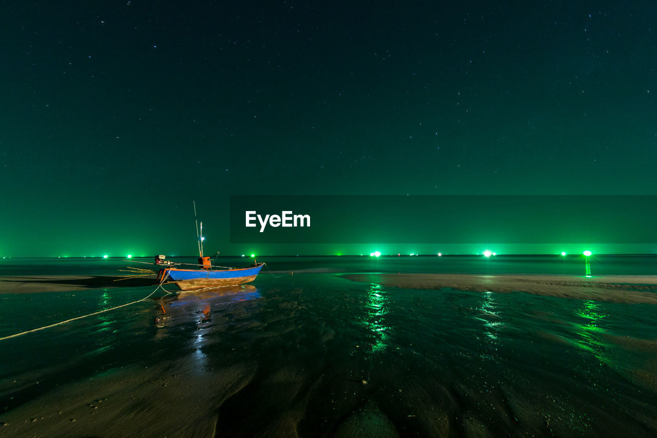 Boat moored in sea against sky at night