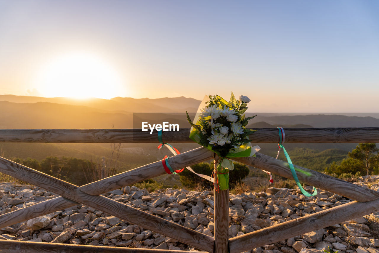 Memorial buquet flowers tied on a wooden fence, outdoors.