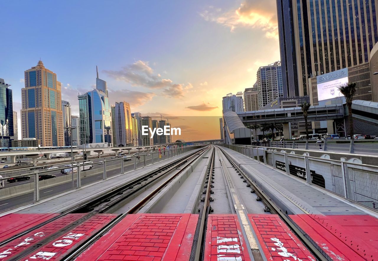 architecture, city, built structure, sky, building exterior, metropolitan area, cityscape, transportation, skyscraper, office building exterior, transport, landscape, rail transportation, railroad track, urban skyline, building, track, urban area, skyline, train, sunset, mode of transportation, nature, cloud, public transport, downtown district, travel destinations, road, downtown, city life, travel, business, street, public transportation, business finance and industry, no people, traffic, outdoors, vehicle, metropolis, railroad station, office, residential district, sunlight, red, motion, highway, landmark