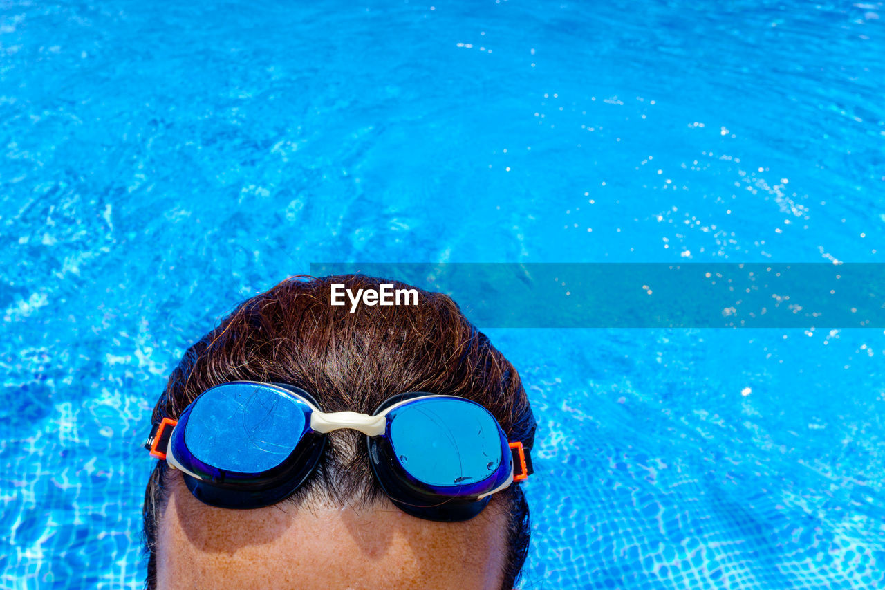 PORTRAIT OF WOMAN SWIMMING UNDERWATER IN POOL