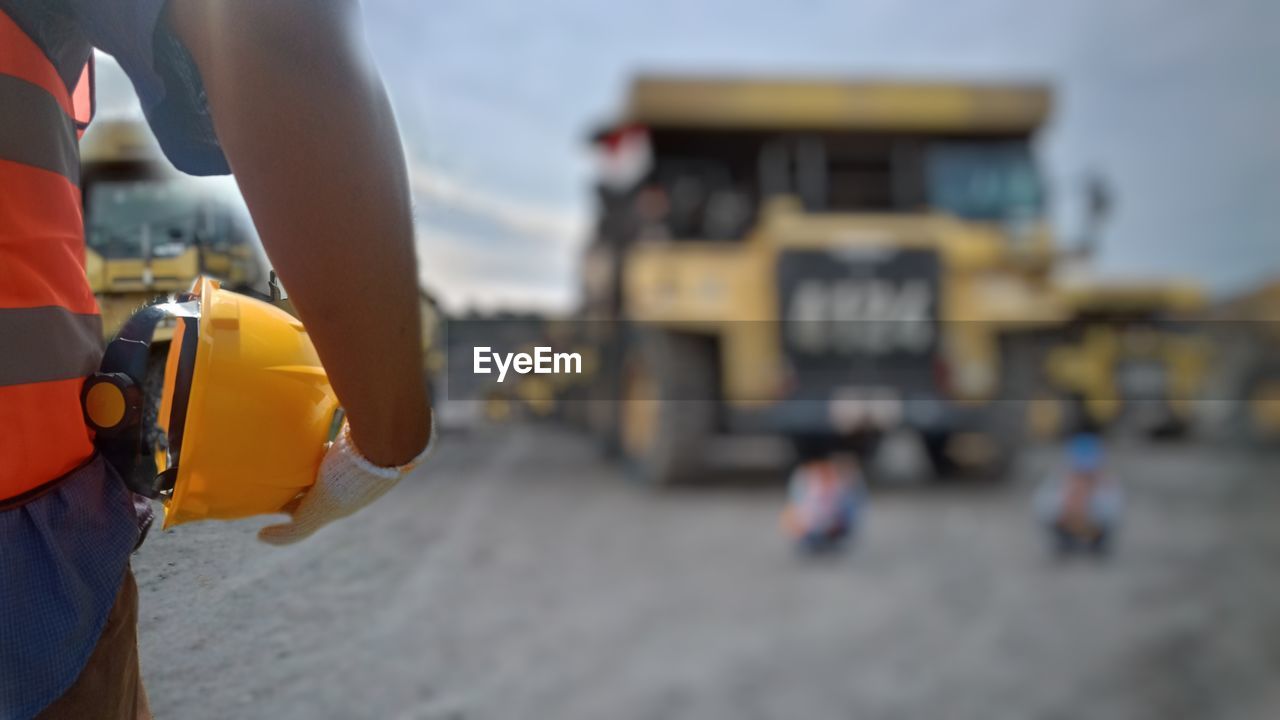 CLOSE-UP OF HAND HOLDING YELLOW DRESS ON BEACH