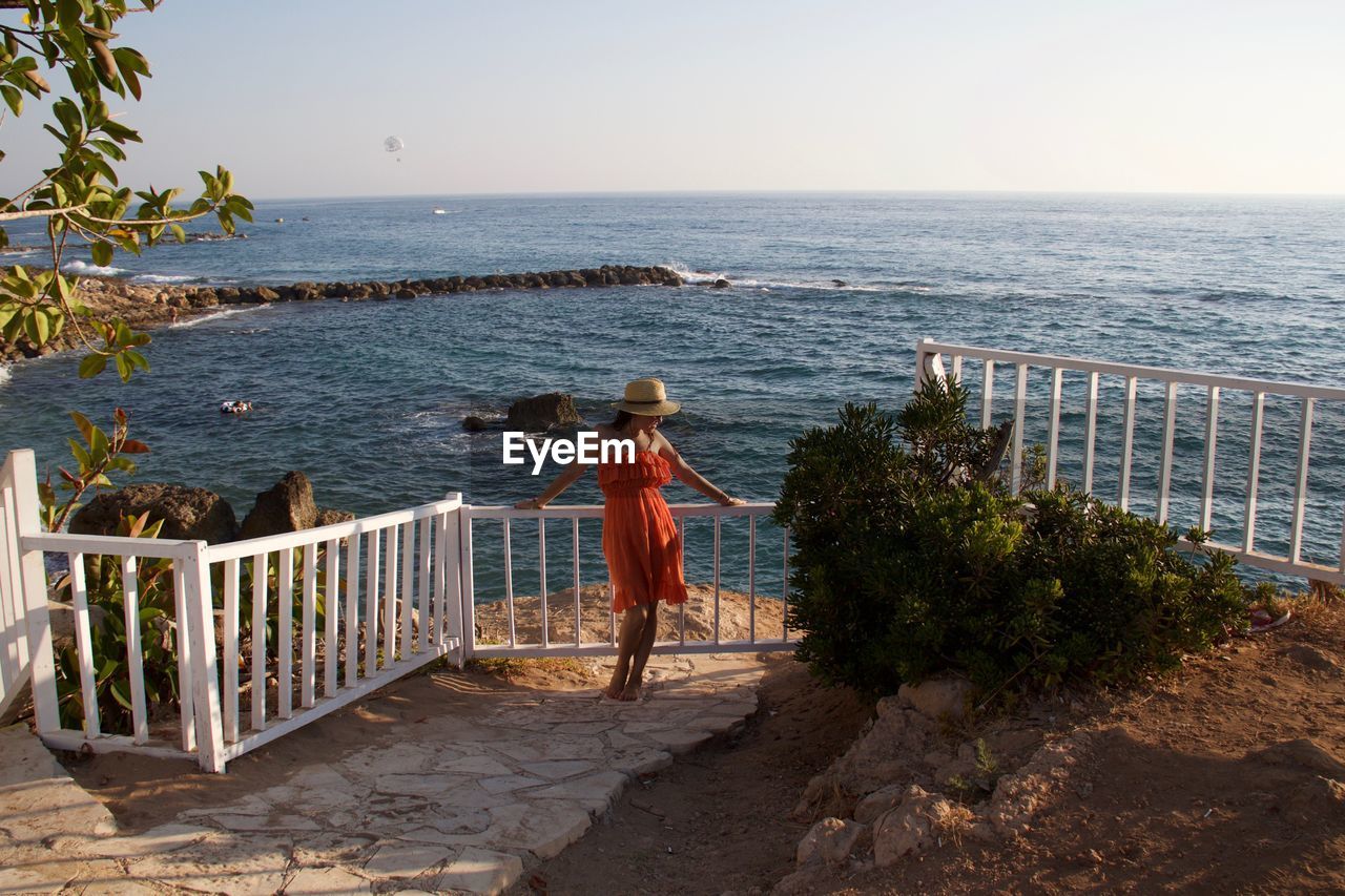 Woman standing at beach against sky