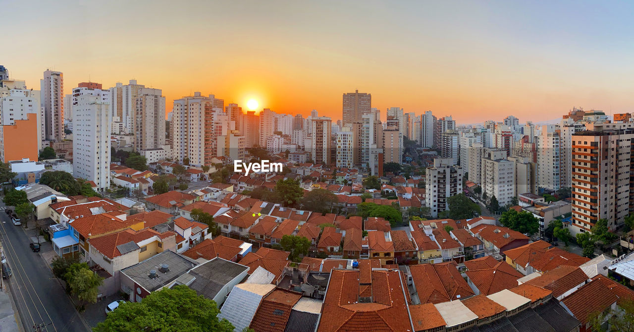 HIGH ANGLE VIEW OF CITY BUILDINGS AGAINST SKY DURING SUNSET