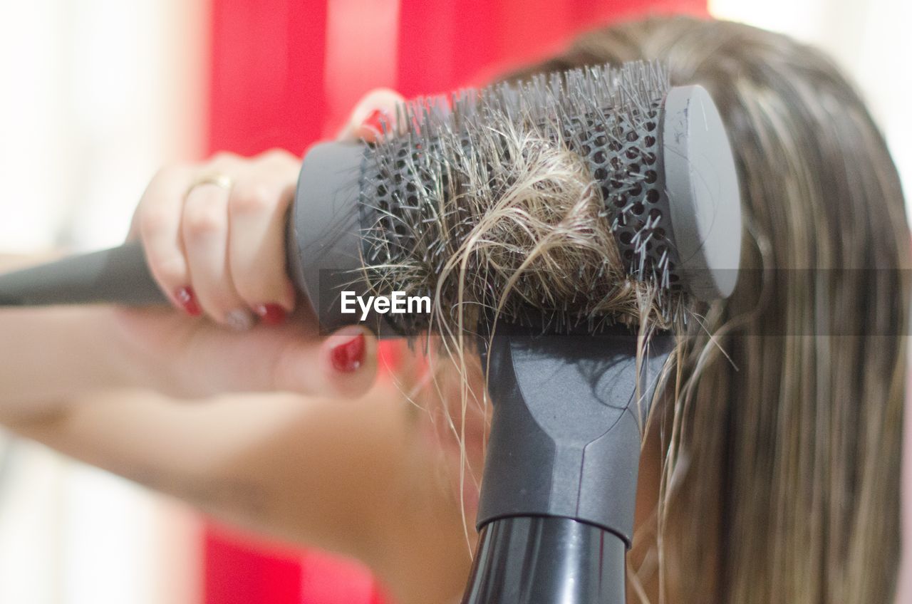 Close-up of woman drying hair with dryer