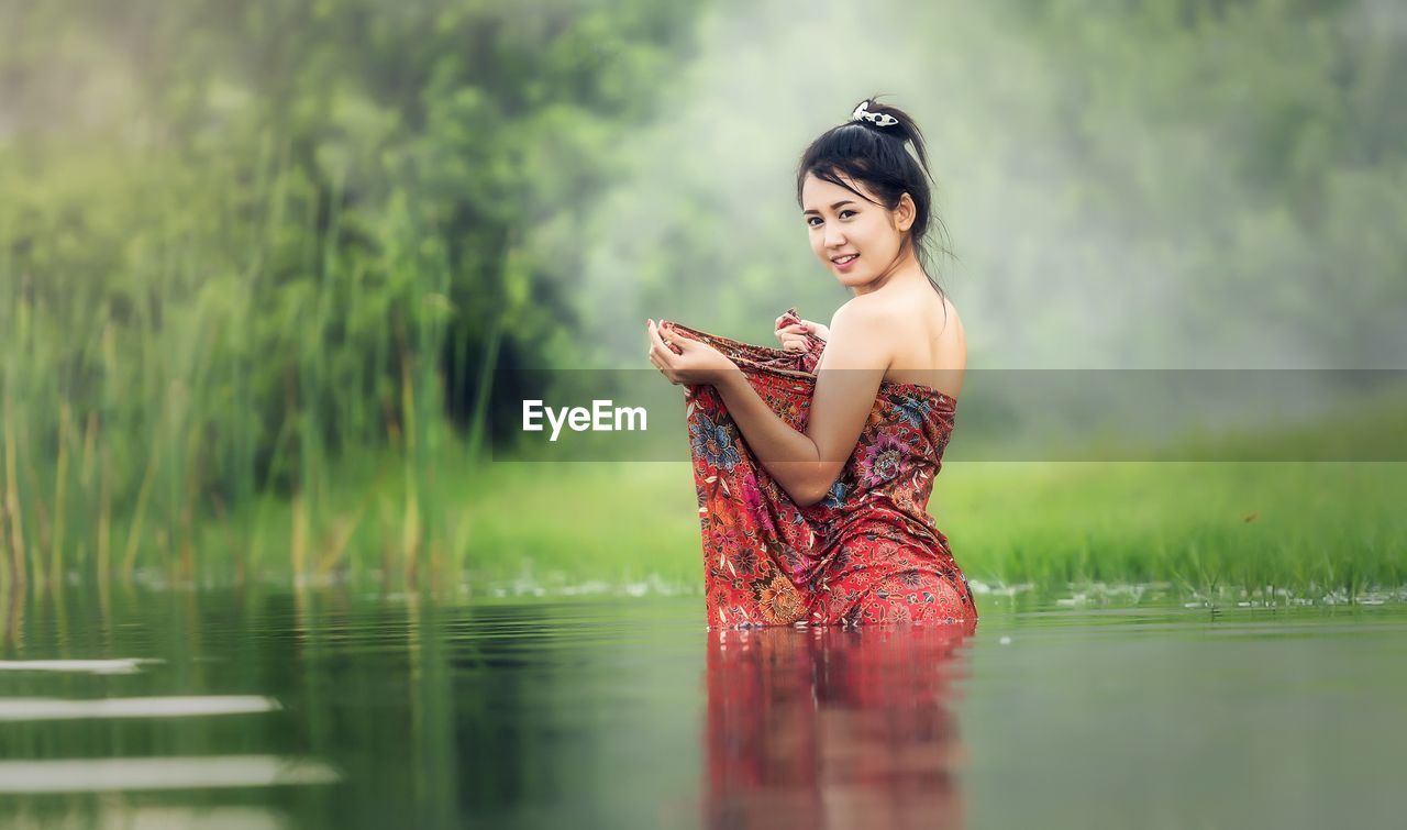 Young woman standing against lake