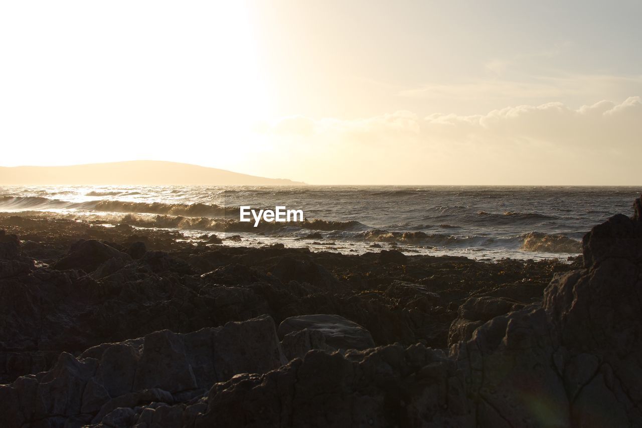 SCENIC VIEW OF BEACH AGAINST SKY AT SUNSET