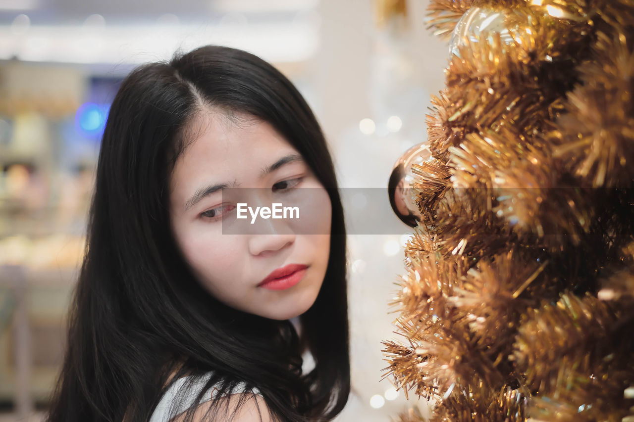 Contemplating young woman standing by christmas tree