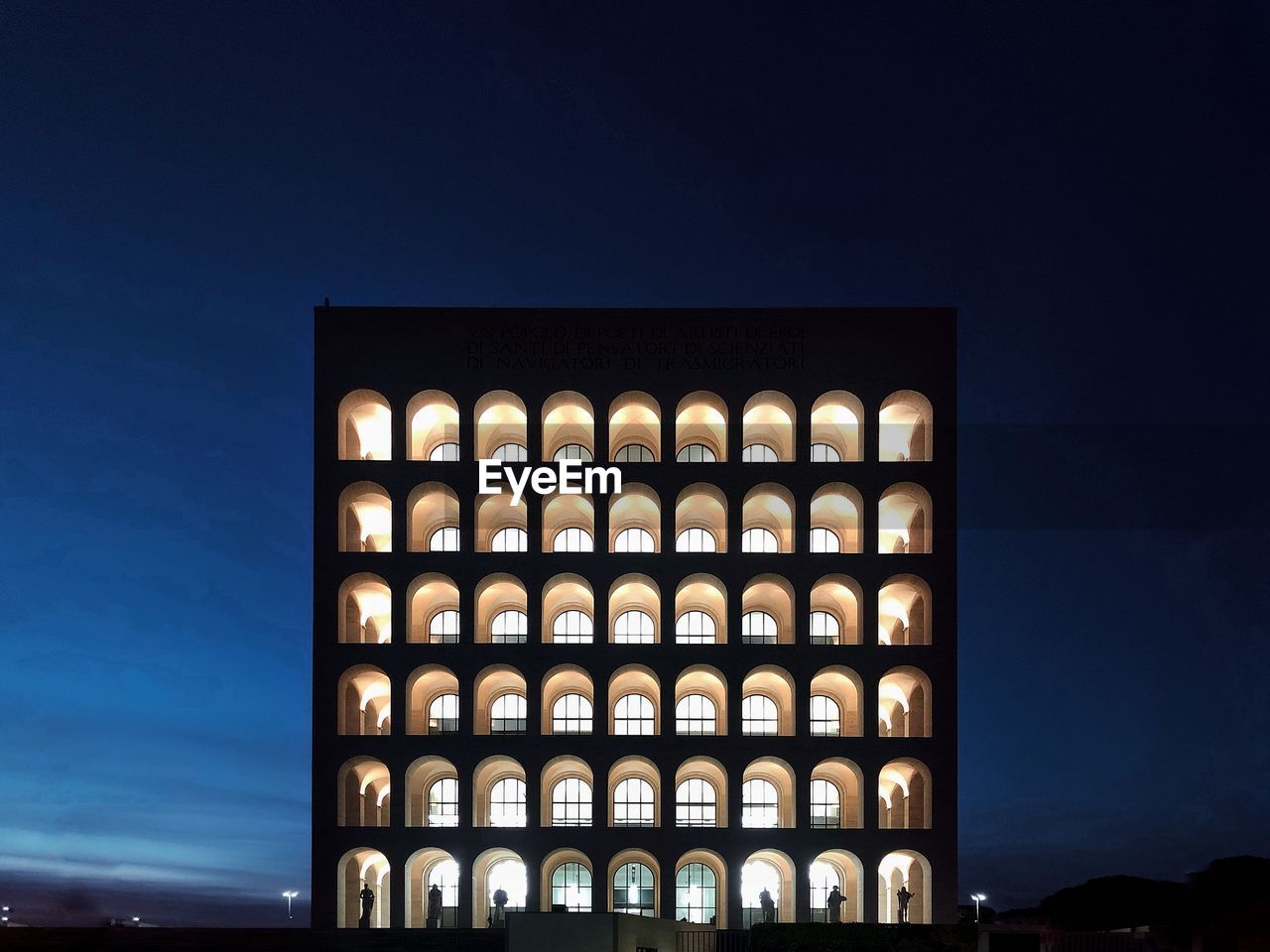 LOW ANGLE VIEW OF ILLUMINATED BUILDING AGAINST SKY AT DUSK