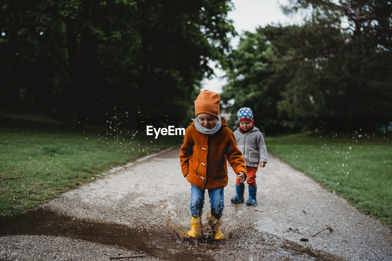 Young kids jumping in the puddles at the park on cloudy day