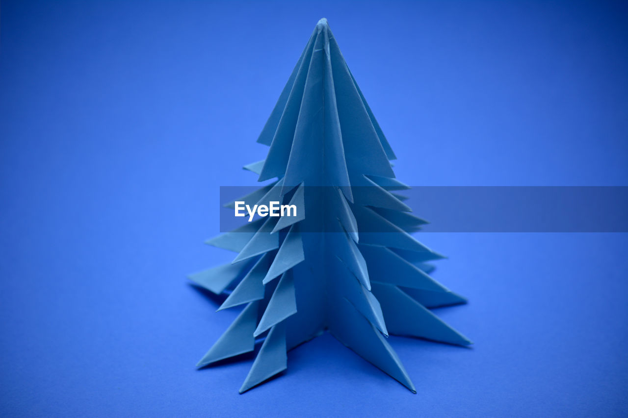 Blue origami christmas tree on a blue background.