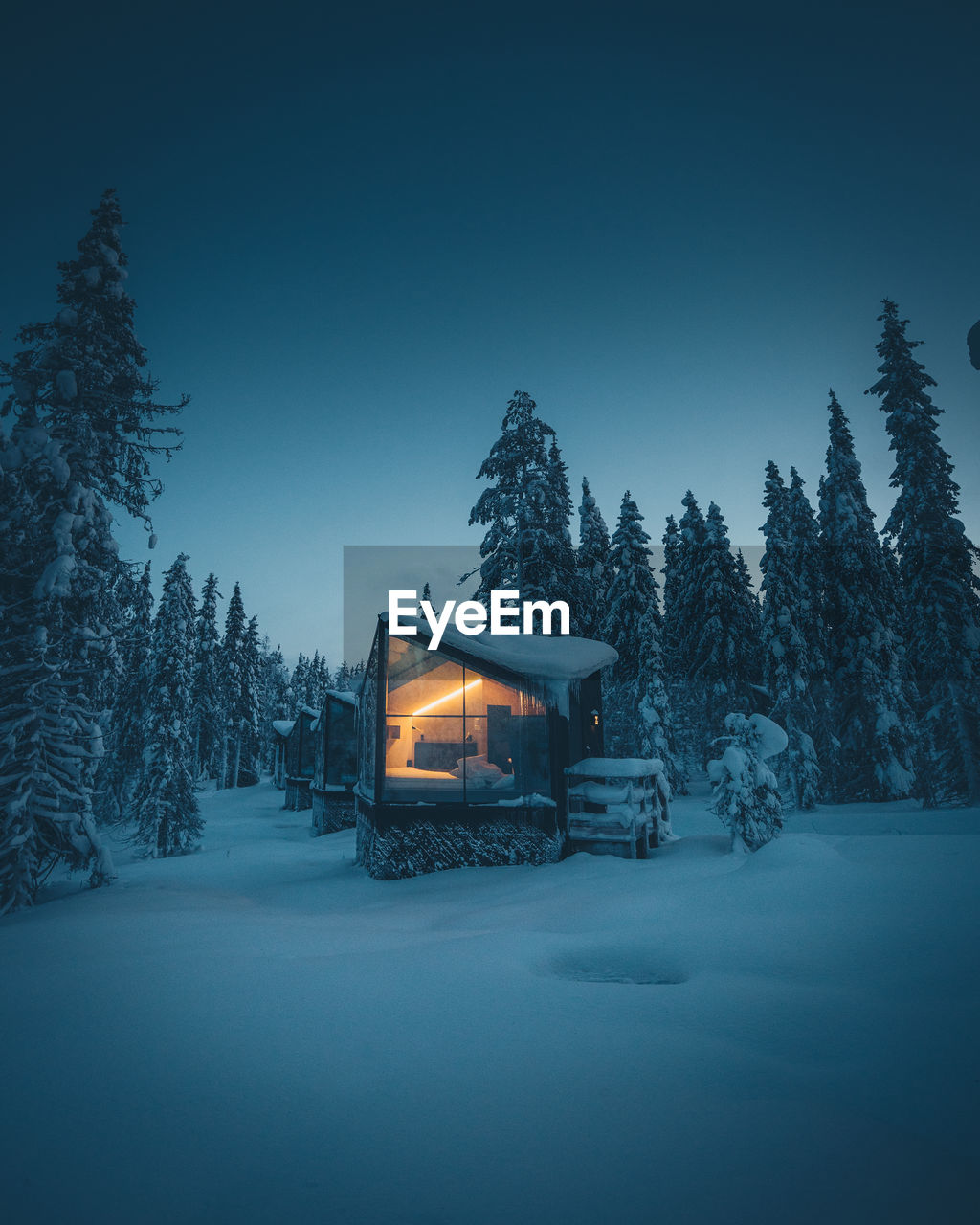 Snow covered cabin and trees against clear sky